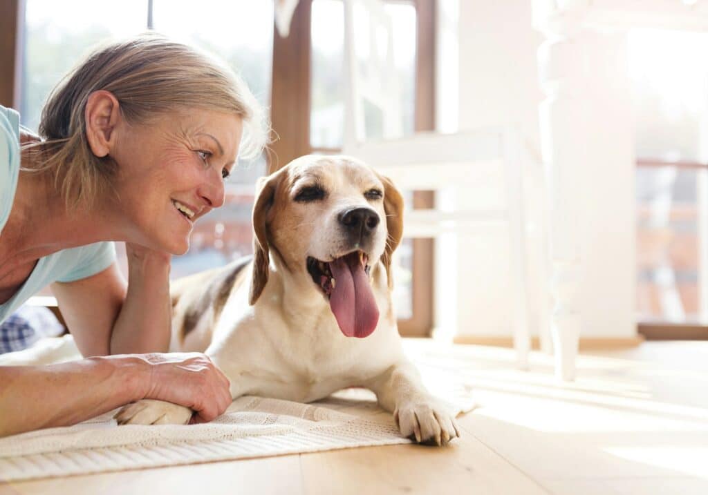 Ältere Frau mit ihrem Hund auf dem Fussboden in ihrem Haus