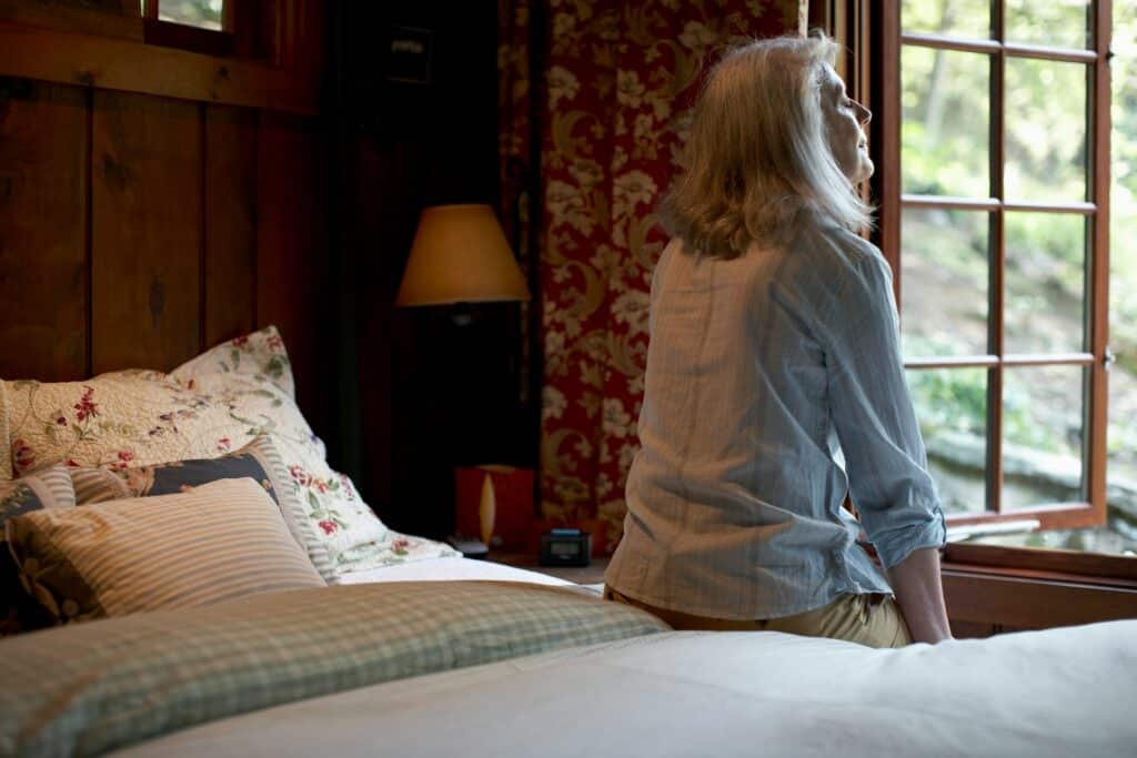 Frau sitzt auf einem Bett im Schlafzimmer mit frischer Raumluft für Allergiker